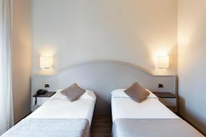 2 letti posti uno accanto all'altro in una stanza di Mokinba Hotels Baviera a Milano