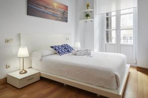 a white bedroom with a large bed and a window at Itsaskirri - Basque Stay in Donostia-San Sebastián