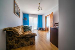 a living room with a couch and blue curtains at Ośrodek Zacisze in Rozewie