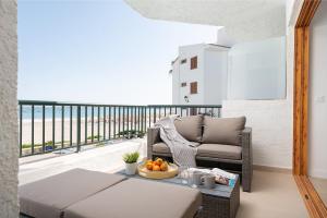 a room with a balcony with a couch and a table at Beachside Alcudia in Port d'Alcudia