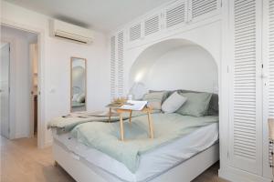 a white bedroom with a bed with a table on it at Beachside Alcudia in Alcudia