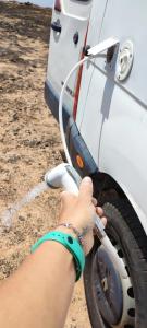 a person washing a white car with a hose at Se alquila magnifica Camper in Costa Teguise