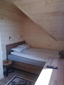 a bed in a wooden cabin with a table at DOMEK POD LIMBAMI V in Kluszkowce