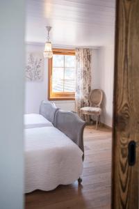 1 dormitorio con 1 cama, 1 silla y 1 ventana en Casa Pasch - Boutique Bed and Breakfast in Cumpadials, en Sumvitg
