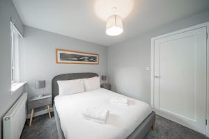 a white bedroom with a bed and a lamp at Church Court in Broughty Ferry