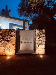 un mur en pierre avec un panneau devant un bâtiment dans l'établissement B&B Quasimare, à Porto Cesareo