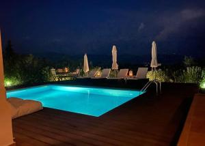 uma piscina à noite com cadeiras e guarda-sóis em Georges Villa Galaxidi, family, pool and garden em Galaxidi