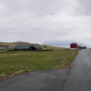 een weg naast een veld en een schuur bij Scenic Village / Nature / Cozy House / 4 BR in Viðareiði