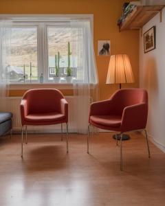 twee stoelen en een lamp in een kamer met een raam bij Scenic Village / Nature / Cozy House / 4 BR in Viðareiði