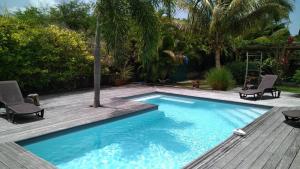 a swimming pool with two chairs and a wooden deck at VILLA Ti'OUITE in Surgy