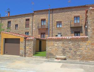 ein großes Backsteingebäude mit zwei Garagentüren und einem Hof in der Unterkunft Casa Fuente Salada - Vinuesa in Vinuesa