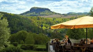 a group of people sitting at a table under an umbrella at Panoramahotel Lilienstein in Königstein an der Elbe