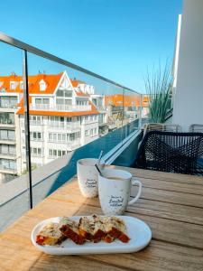 een bord eten en twee kopjes koffie op een balkon bij la MERéMOI - Duplex Knokke with balcony and free parking in Knokke-Heist