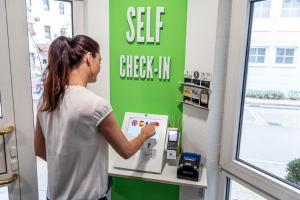 una mujer está usando una máquina de autocontrol en una tienda en Hotel Princess Self Check-In en Plochingen