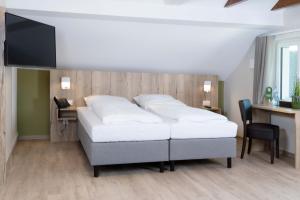 een slaapkamer met een bed, een bureau en een televisie bij Gästehaus Dillertal in Bruchhausen-Vilsen