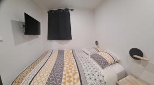 Un dormitorio con una cama con un televisor en la pared. en Chez Rémy, en Les Angles