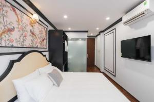 a bedroom with a white bed and a flat screen tv at Charming Moon Hotel in Hanoi