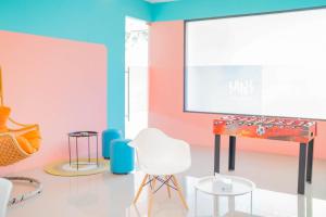 a room with a piano and chairs and a screen at Sans Hotel Widarasari Cirebon in Cirebon