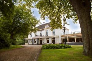 an exterior view of a white house with a tree at Landgoed Hotel & Restaurant Carelshaven in Delden