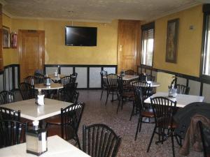 a restaurant with tables and chairs and a television on the wall at Hostal El Sevillano in Rus