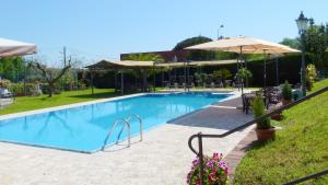 a large swimming pool with an umbrella and some chairs at Albergo la Luna in Sarzana