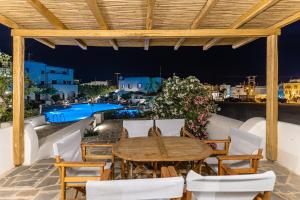 un patio con mesa, sillas y piscina en Naxian Queen Luxury Villas & Suites, en Agia Anna de Naxos