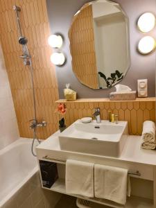 W łazience znajduje się umywalka, lustro i wanna. w obiekcie Ditlin Apartmanok w mieście Pápa