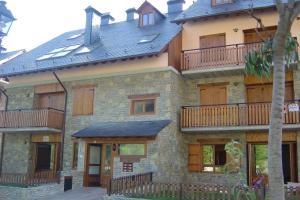 a large stone building with wooden balconies on it at APARTMENTSUITESPAIN BAQUEIRA JARDIn in Esterri d'Àneu