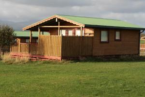 a wooden house with a green roof in a field at Eldborg Cabins and Guesthouse in Kolbeinsstaðir