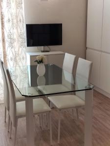 a glass dining room table with white chairs and a television at Dimora Ketty in Noci