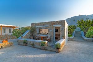 una casa in pietra con un tavolo e alcune scale di IL Vento Suites a Mykonos Città