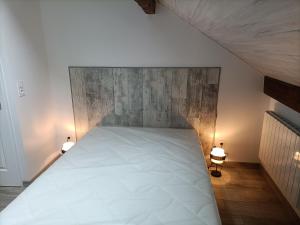 a bedroom with a white bed with a wooden headboard at La clé du Champ in Le Clerjus