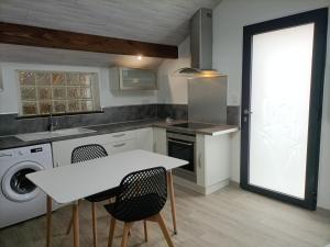 a kitchen with a table and a sink and a washing machine at La clé du Champ in Le Clerjus