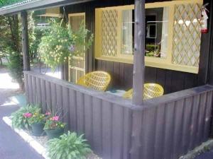 una casa con 2 sillas y un porche con plantas en Amber Lantern One-Bedroom Cottage, en Lake George