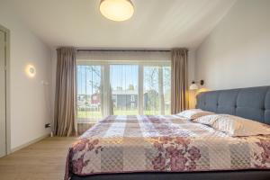a bedroom with a bed and a large window at Vila „Perkūnas“ in Palanga