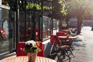 een rij tafels en stoelen met bloemen op een stoep bij Storyhotel Bergischer Hof Königswinter in Königswinter