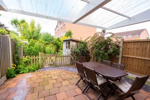 a patio with a wooden table and chairs at Bright & modern 4 bedroom townhouse in Stafford