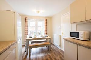 a kitchen with a small table and a microwave at Bright & modern 4 bedroom townhouse in Stafford