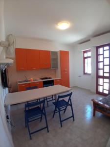 リド・マリーニにあるCasa Lido Mariniのキッチン(オレンジ色のキャビネット、テーブル、椅子付)
