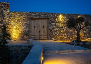 KK Mykonos Village في مدينة ميكونوس: مبنى حجري بباب خشبي في الليل
