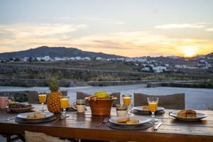 a wooden table with plates of food and glasses of orange juice at KK Mykonos Village in Mikonos