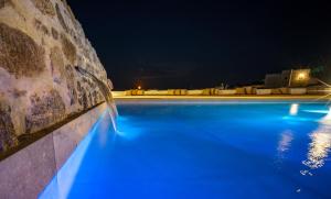 een zwembad 's nachts met blauwe lichten bij KK Mykonos Village in Mykonos-stad