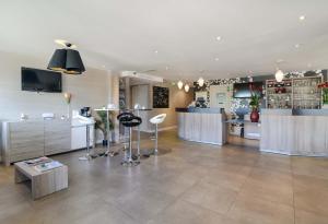 a large room with a bar with stools in it at Kyriad Lyon Est - Saint Bonnet De Mure in Saint-Bonnet-de-Mure