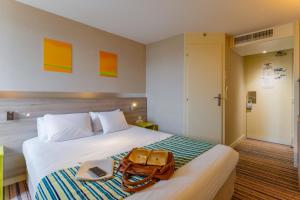 a hotel room with a bed with a purse on it at Kyriad Lyon Est - Saint Bonnet De Mure in Saint-Bonnet-de-Mure