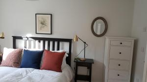 a bedroom with a bed with colorful pillows and a mirror at The Cottage in Bristol