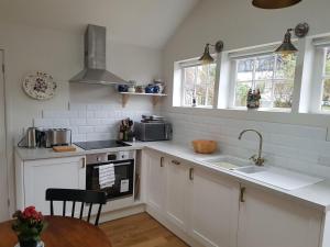 a kitchen with white cabinets and a sink and windows at The Cottage in Bristol