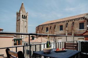 un tavolo con un cesto di frutta su un balcone con torre dell'orologio. di Palazzetto Barnaba a Venezia
