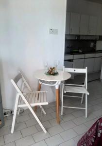 una mesa blanca con 2 sillas y copas de vino en 1 bedroom apartment with a magnificent sea view, en Limassol