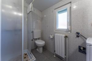 baño con aseo y ducha y ventana en Apartmani Mirela, en Banjole