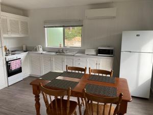 eine Küche mit einem Holztisch und einem weißen Kühlschrank in der Unterkunft Aruma Cottage Bruny Island in Alonnah